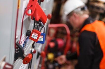 Closeup of Brady LOTO devices with a worker in background.