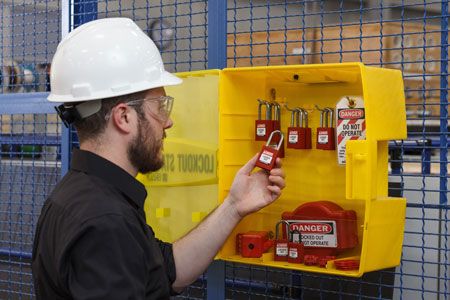 Man in hardhat removes items from yellow LOTO box.