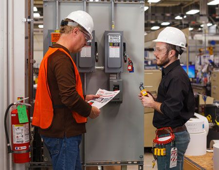 Workers in hardhats review LOTO procedures with equipment.