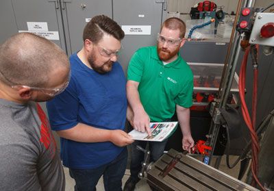 Three men review LOTO procedure with equipment.