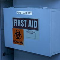 A first aid kit with a clearly visible label mounted to a wall.