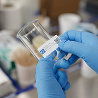 A lab technician applies a label to a flask.