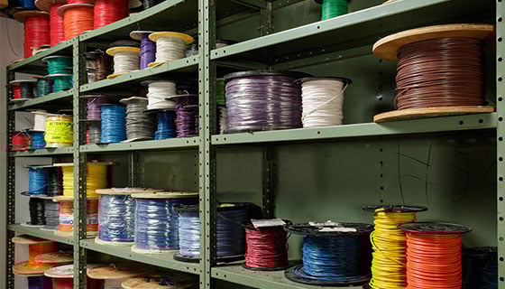 Many spools of brightly colored wire on a shelf. 