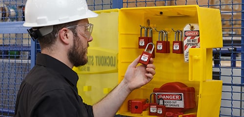 An industrial worker removing a LOTO padlock from a lockout station.