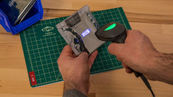 Person using a CR1500 to scan a barcode on a reflective surface.
