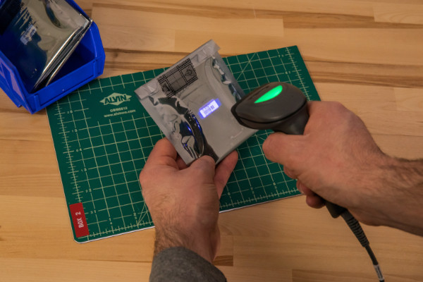 Person using a CR1500 to scan a barcode on a reflective surface.