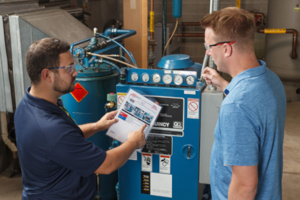 Two people reviewing the lockout procedure for an industrial compressor. 