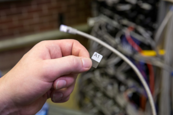 Person attaching a wrap-around label to a network cable.