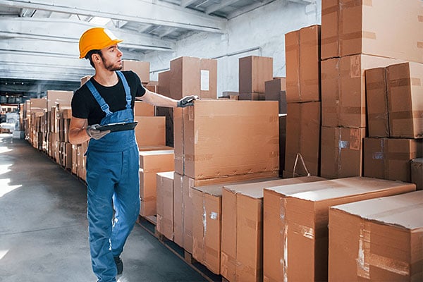 A warehouse worker examining a large collection of boxes.