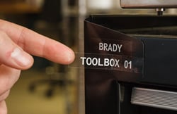 Fingers showing a clear Brady toolbox label.
