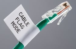 Closeup of a green ethernet cable with a label.