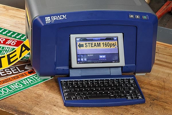 A Brady BBP37 printer creating safety labels on a workbench.