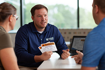 Brady sales representative talking to two people showing arc flash labels.