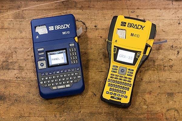 Two Brady portable printers sit on a wooden bench.
