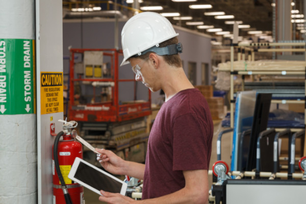 An employee inspecting the tag on a fire extinguisher.
