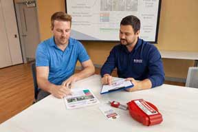 Two men sitting at a table review LOTO procedures.