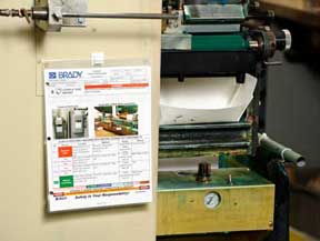 A job safety procedure sheet hanging in a plastic sleeve.