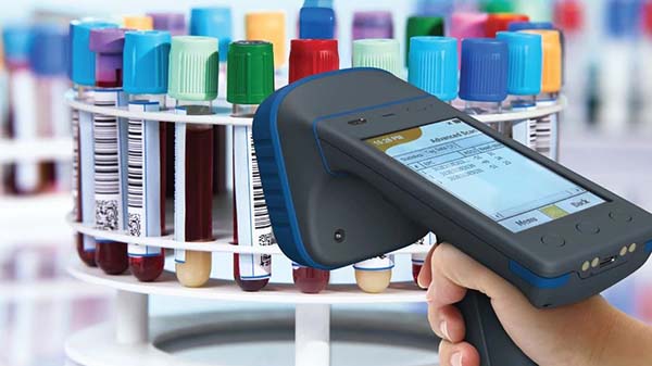 Handheld RFID scanner scanning blood vials in a circular rack.