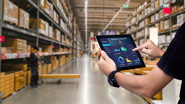 Man holding tablet with data on screen in a warehouse.