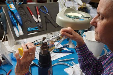 Technician working with wires applies heat to a Brady label. 
