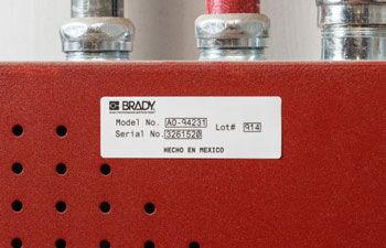 Closeup of a Brady B-423 Polyester Label on red background.