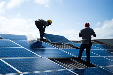 Two men installing solar panels on a roof.