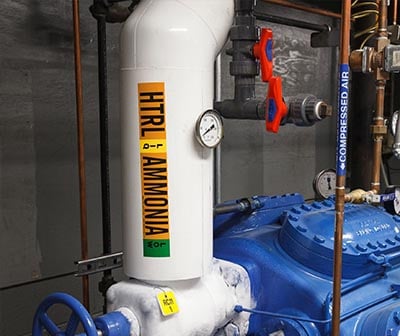 White pipe with valve and orange pipe marker indicating ammonia.