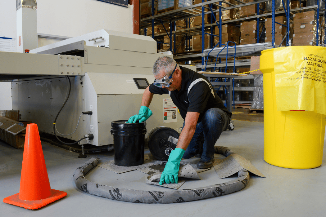 A worker cleans a spill using various spill control safety devices