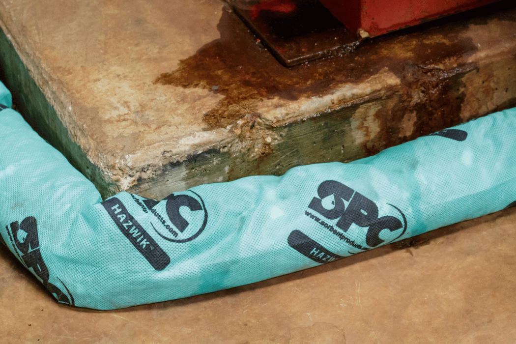 Safety spill boom placed intentionally around a leaking piece of industrial equipment