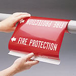 A worker places a red fire protection self adhesive pipe marker on a pipe