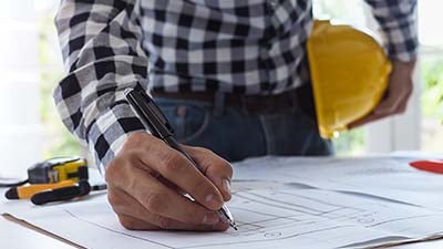 A worker writing out a construction blueprint 