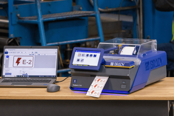 A laptop with software on the screen being used to print tags out of an adjacent printer